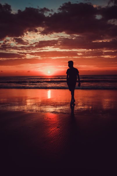 silhouette-of-man-standing-on-beach-during-sunset-3866261